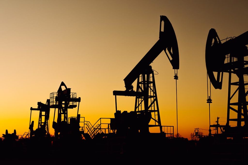 The silhouette of two oil pumps on a beautiful yellow sunset sky. Oil production well in Siberia